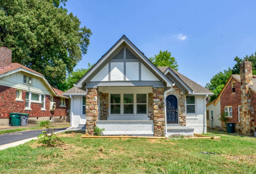 English style home featuring a porch and a front lawn