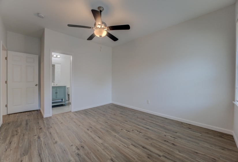 Unfurnished bedroom featuring hardwood / wood-style floors, ceiling fan, and ensuite bathroom
