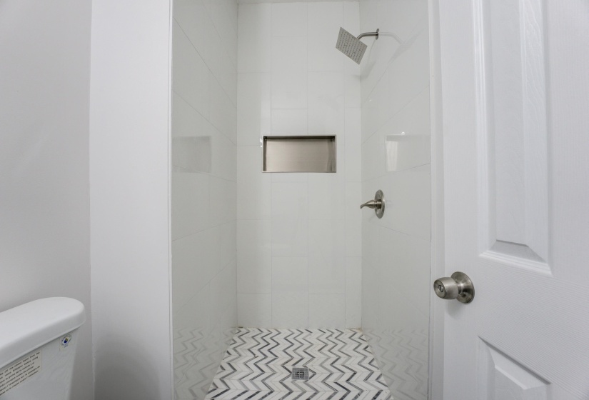 Bathroom featuring tiled shower and toilet