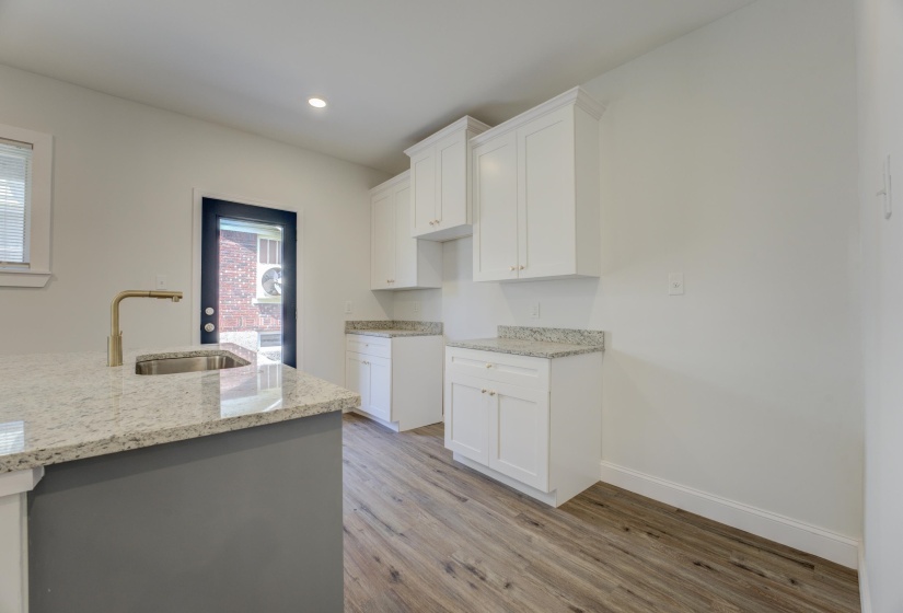 Kitchen featuring white cabinets, sink, light wood-type flooring, and light stone counters