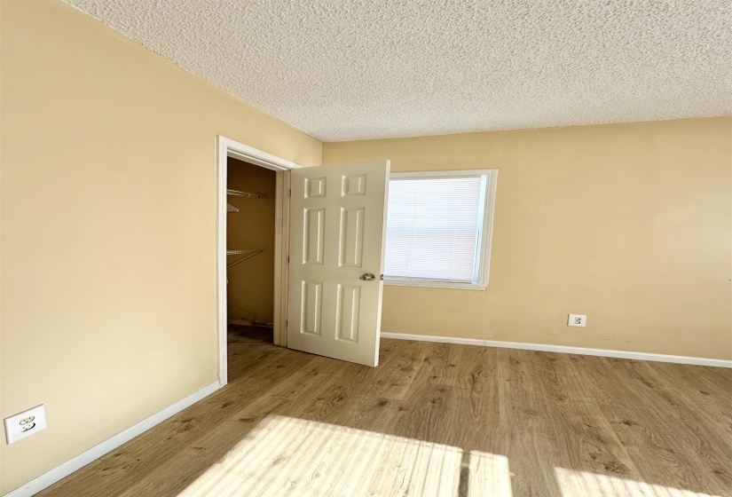 Unfurnished bedroom with light hardwood / wood-style flooring, a textured ceiling, and a closet