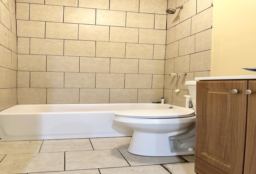Full bathroom featuring vanity, tile patterned floors, tiled shower / bath, toilet, and tile walls