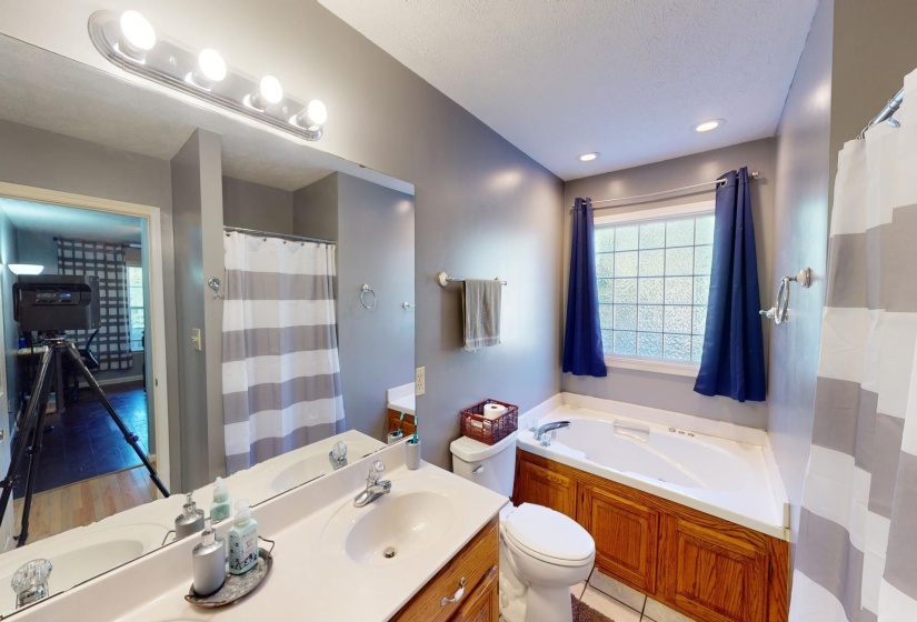 Bathroom with hardwood / wood-style flooring, toilet, a tub to relax in, vanity, and a textured ceiling