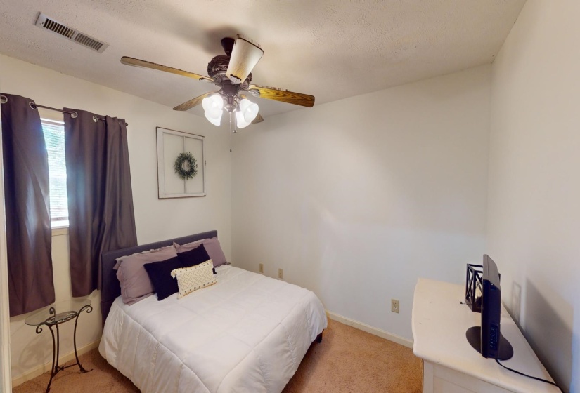 Carpeted bedroom with a textured ceiling and ceiling fan