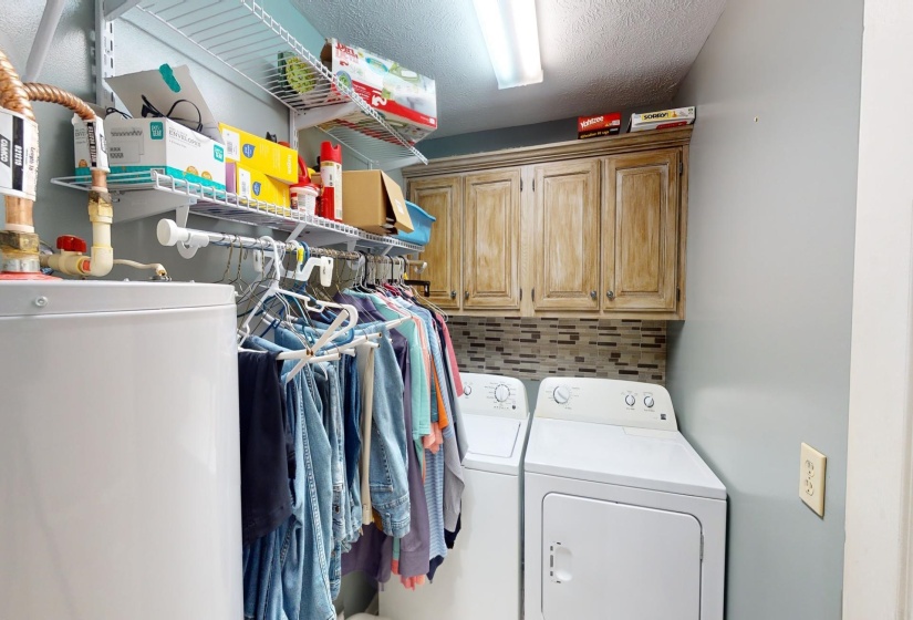 Laundry area featuring a textured ceiling, washing machine and dryer, and cabinets