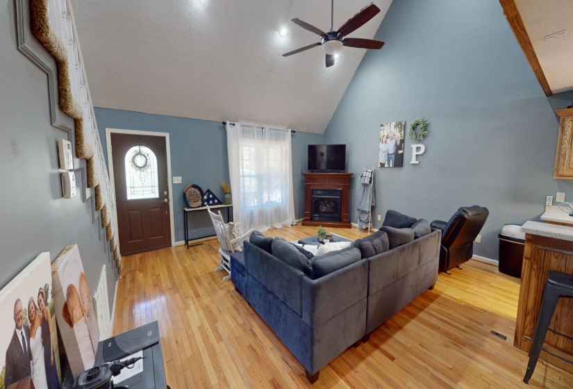 Living room featuring ceiling fan, high vaulted ceiling, and light hardwood / wood-style flooring