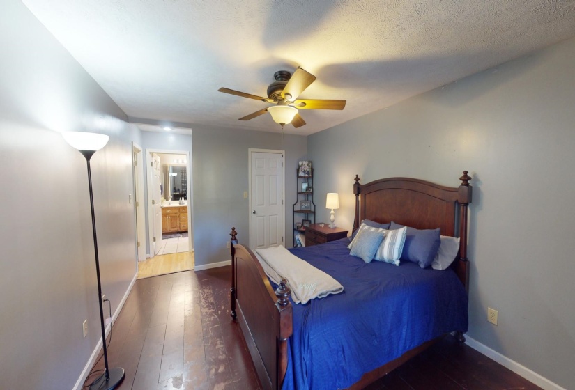 Bedroom featuring a textured ceiling, ensuite bath, dark wood-type flooring, and ceiling fan
