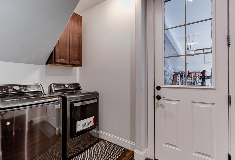 Washroom featuring hardwood / wood-style flooring, washing machine and clothes dryer, a healthy amount of sunlight, and cabinets