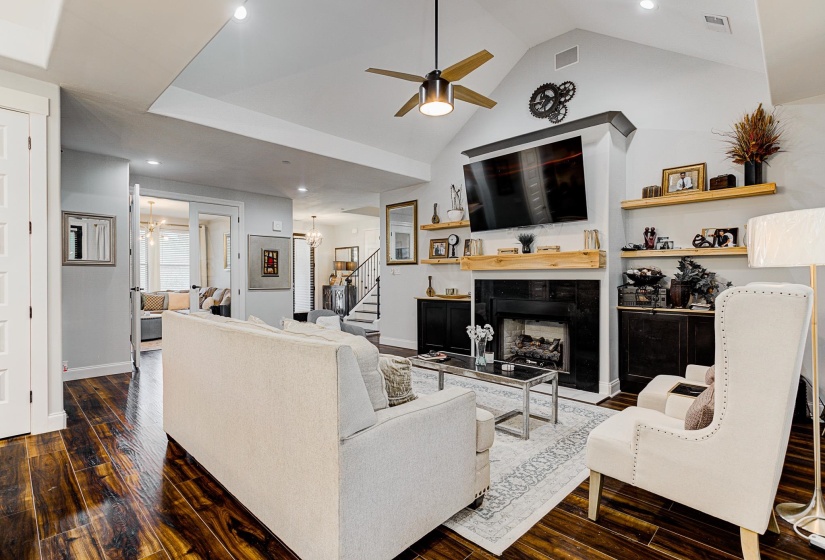 Featuring hardwood / wood-style floors, high vaulted ceiling, a fireplace, and ceiling fan.