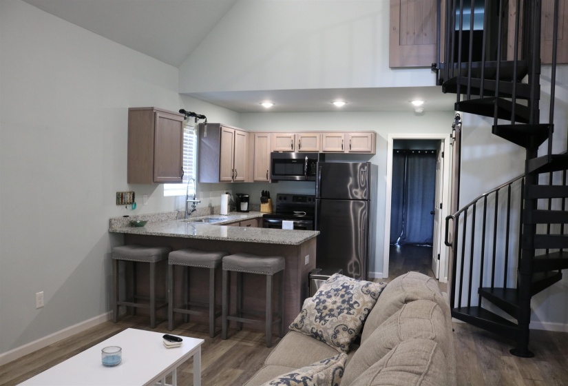 Kitchen featuring stainless steel appliances, sink, kitchen peninsula, dark hardwood / wood-style floors, and vaulted ceiling