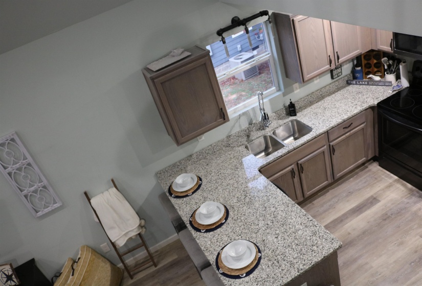 Kitchen featuring black electric range oven, light hardwood / wood-style flooring, sink, and light stone countertops