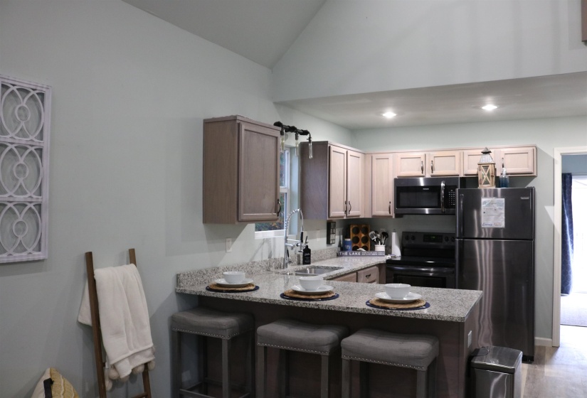 Kitchen with stainless steel appliances, sink, kitchen peninsula, and vaulted ceiling