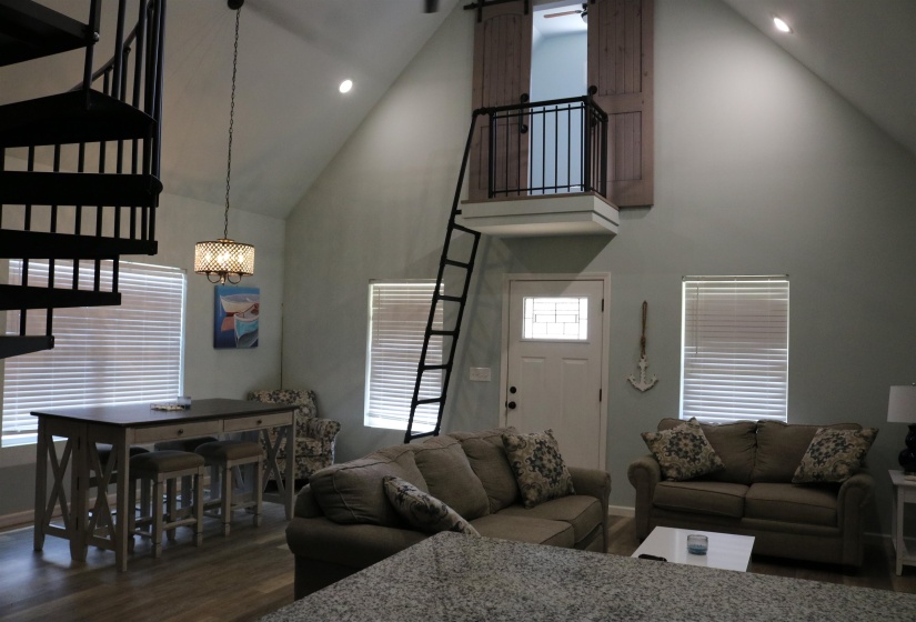 Living room featuring high vaulted ceiling, an inviting chandelier, dark wood-type flooring, and a barn door