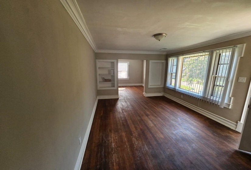 Spare room featuring dark wood-type flooring and crown molding