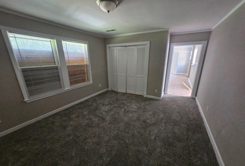 Unfurnished bedroom featuring a closet, dark carpet, and ornamental molding