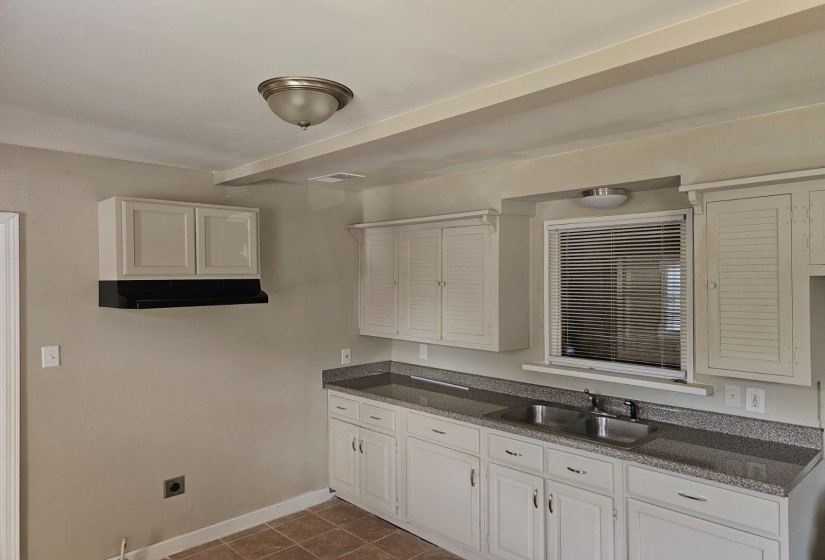 Kitchen with dark tile patterned flooring, white cabinetry, and sink