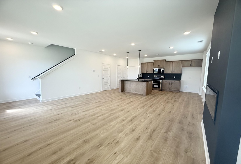 Kitchen with open floor plan, stainless steel appliances, recessed lighting, dark countertops, and light wood finished floors