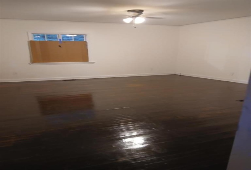 Empty room featuring ceiling fan and dark wood-type flooring