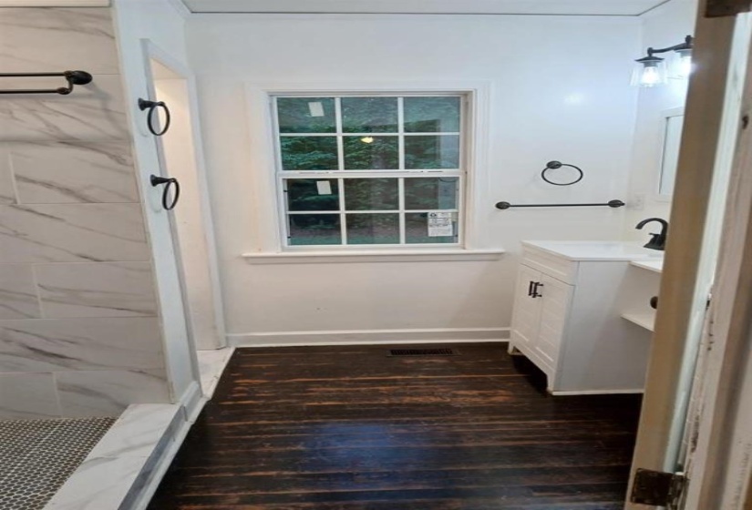 Bathroom with vanity, a tile shower, and wood-type flooring