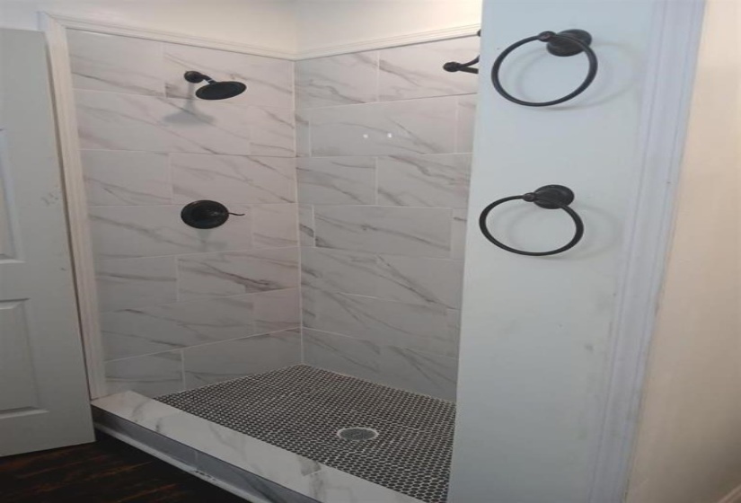 Bathroom with a tile shower and hardwood / wood-style floors