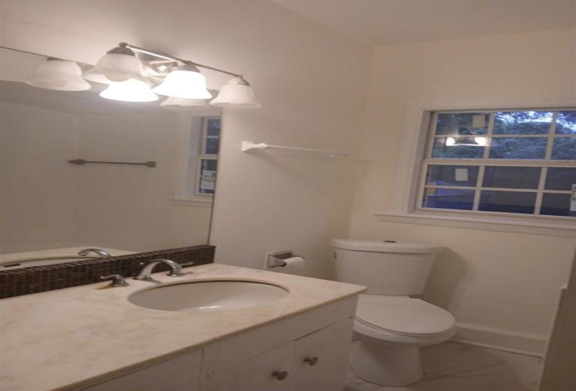 Bathroom featuring tile patterned floors, toilet, vanity, and an inviting chandelier