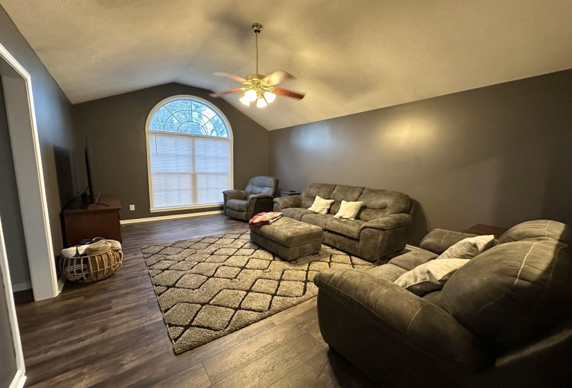 Living room with dark hardwood / wood-style floors, ceiling fan, and vaulted ceiling