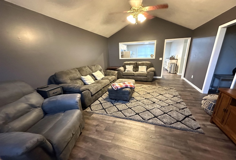Living room featuring dark hardwood / wood-style floors, ceiling fan, and vaulted ceiling