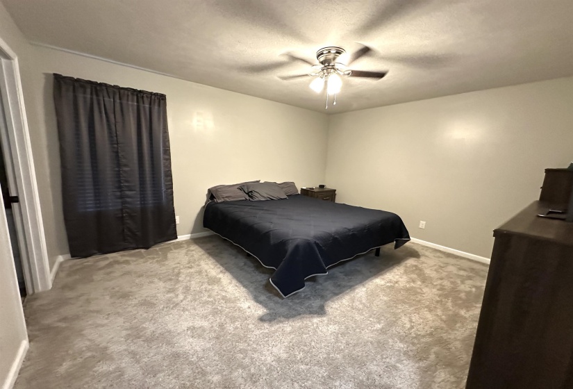 Carpeted bedroom with ceiling fan and a textured ceiling