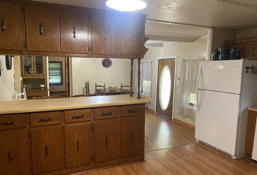 Kitchen with freestanding refrigerator, light wood-style floors, brown cabinets, and light countertops