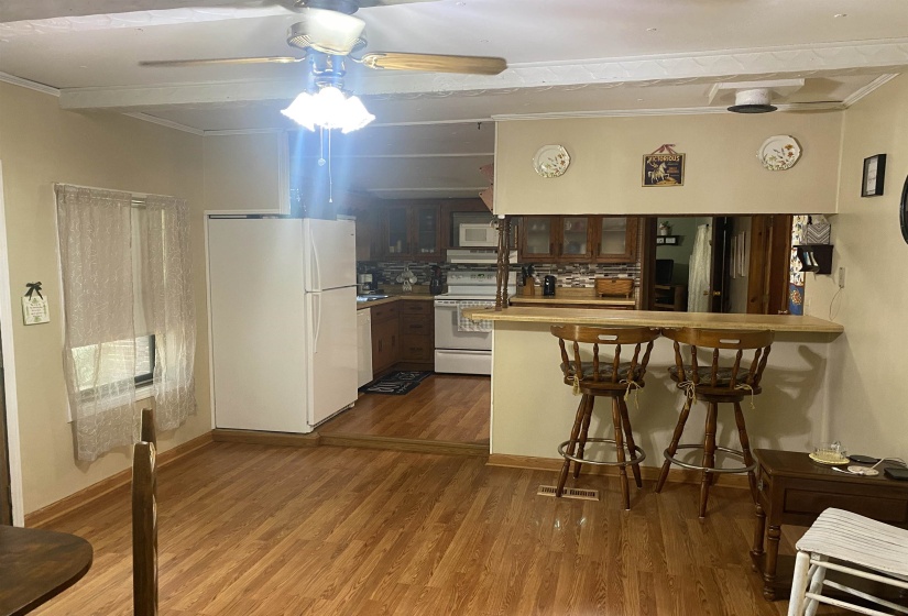Kitchen featuring white appliances, ceiling fan, a peninsula, ornamental molding, and glass insert cabinets