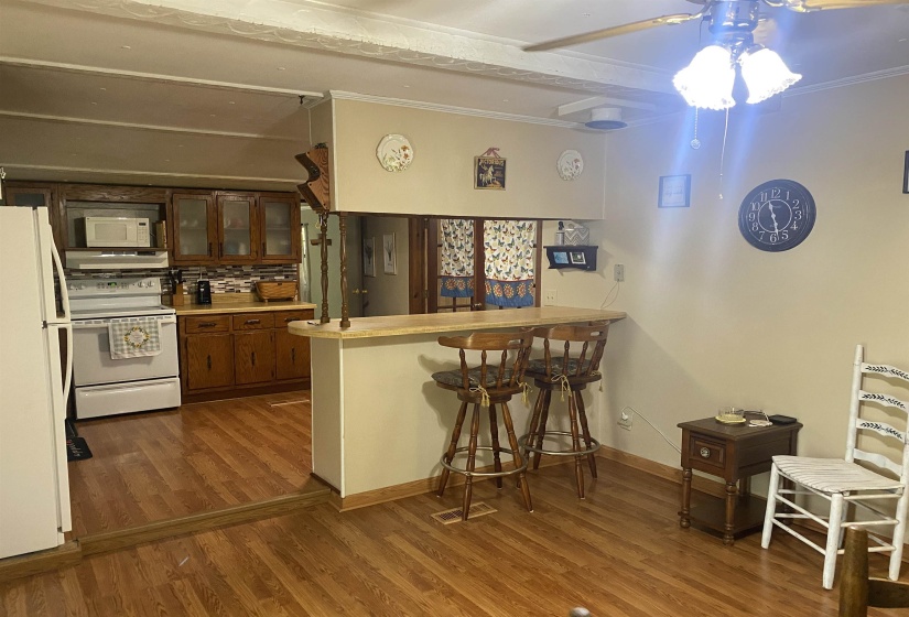 Kitchen featuring white appliances, ornamental molding, wood finished floors, a peninsula, and glass insert cabinets