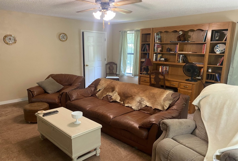 Living room with carpet floors, ceiling fan, and a textured ceiling