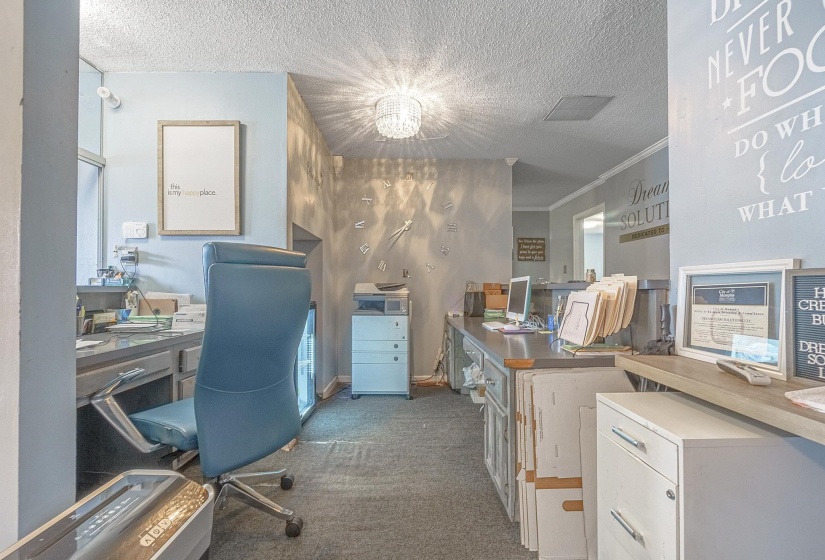 Home office with crown molding, dark carpet, and a textured ceiling