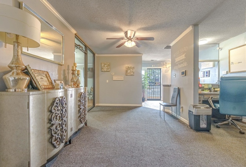 Hallway with carpet floors, ornamental molding, and a textured ceiling