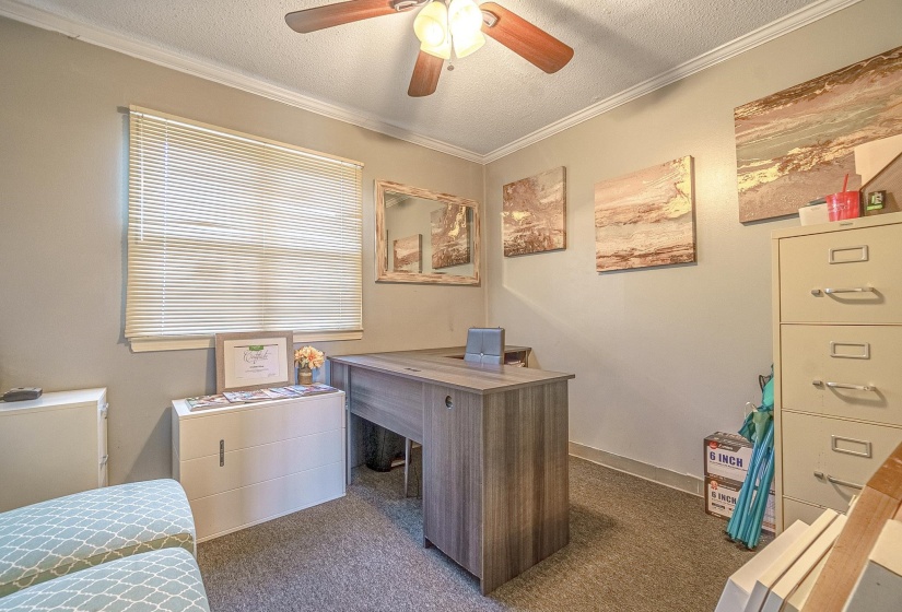 Office area featuring ceiling fan, crown molding, a textured ceiling, and dark colored carpet