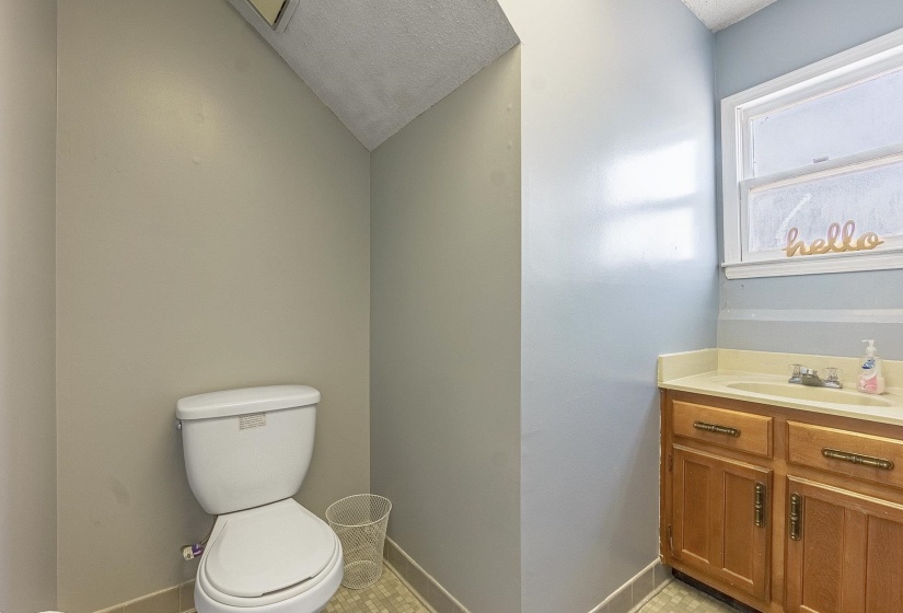 Bathroom with lofted ceiling, vanity, toilet, and a textured ceiling
