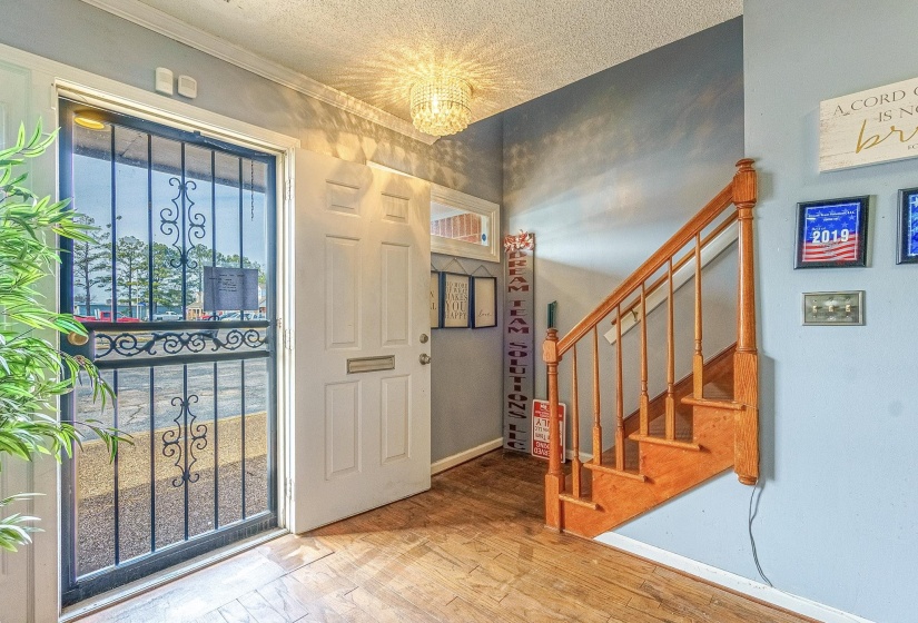 Entrance foyer featuring hardwood / wood-style flooring, ornamental molding, a chandelier, and a textured ceiling