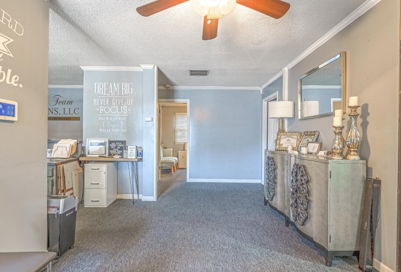 Hall featuring ornamental molding, dark carpet, and a textured ceiling