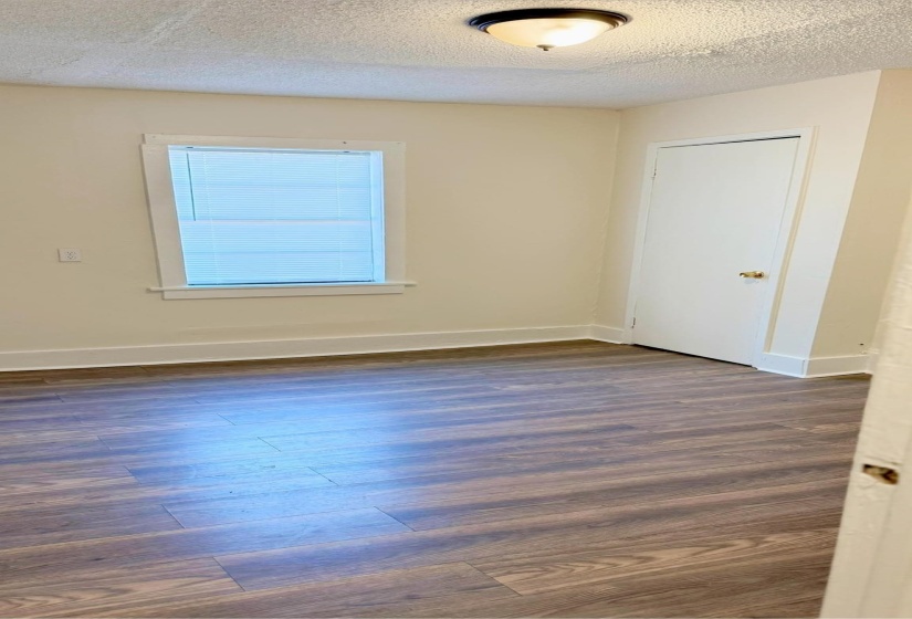 Unfurnished room featuring a textured ceiling and dark hardwood / wood-style floors