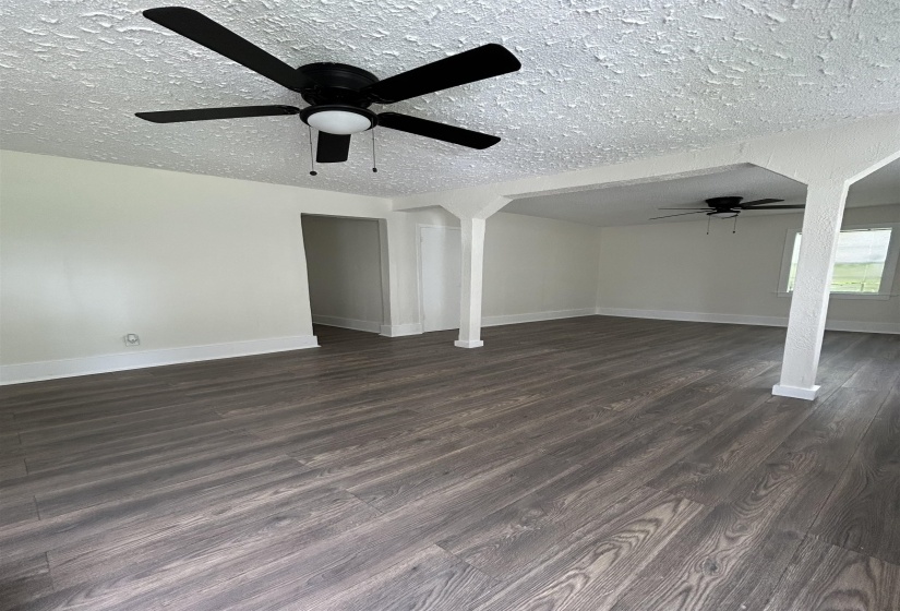 Unfurnished living room with a ceiling fan, dark wood-style floors, and a textured ceiling