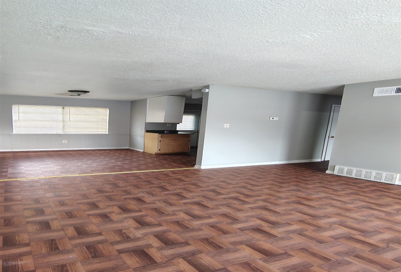 Unfurnished living room with a textured ceiling and dark parquet floors