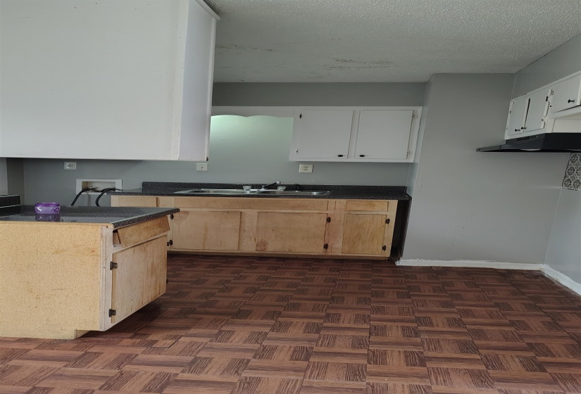 Kitchen featuring a textured ceiling, dark parquet floors, white cabinetry, and sink
