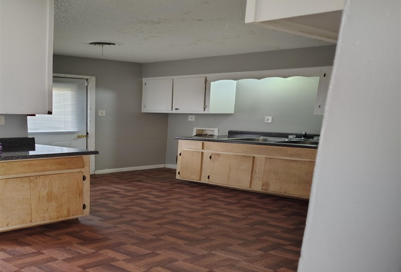 Kitchen with a textured ceiling, light brown cabinets, dark parquet flooring, and sink