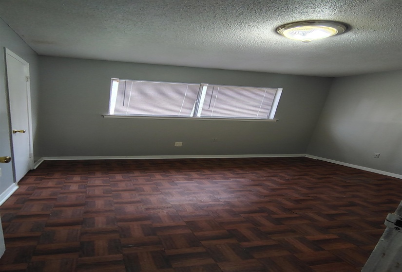 Empty room with dark parquet flooring, a healthy amount of sunlight, and a textured ceiling