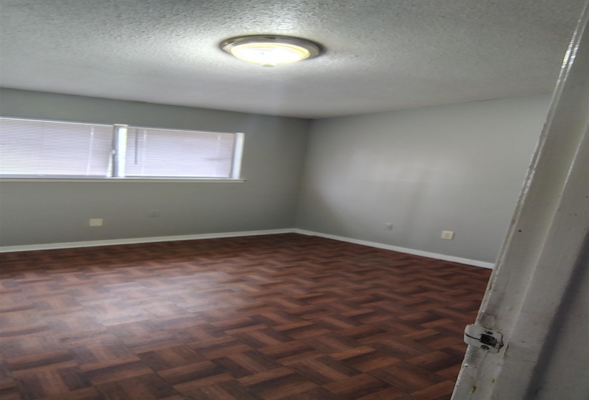 Unfurnished room with dark parquet flooring and a textured ceiling