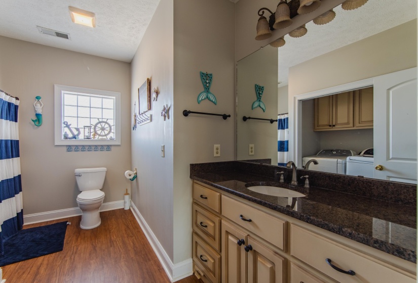 Bathroom featuring vanity, hardwood / wood-style flooring, toilet, independent washer and dryer, and a textured ceiling