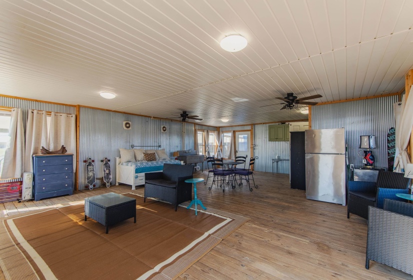 Living room with ceiling fan, wooden walls, and light hardwood / wood-style floors