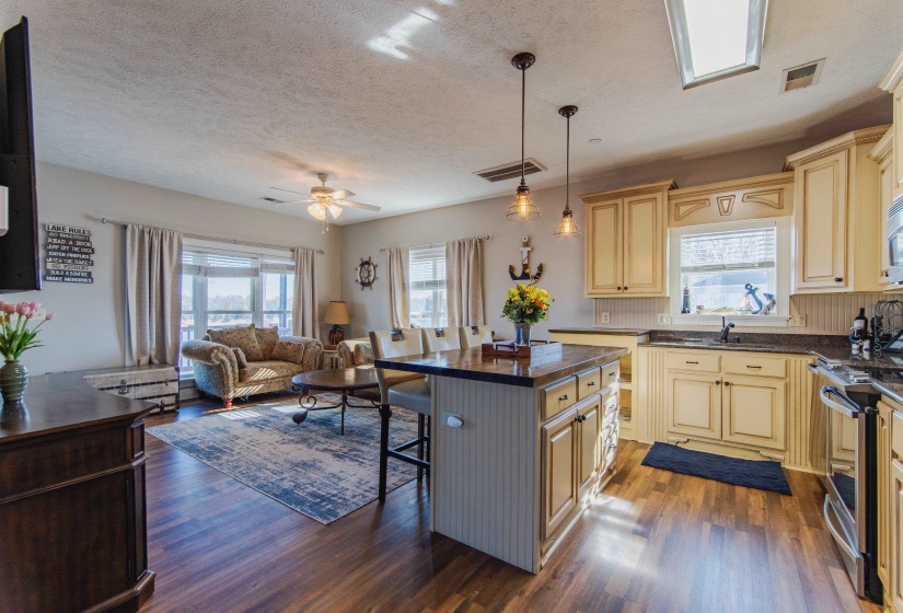 Kitchen featuring a center island, dark wood-type flooring, a kitchen breakfast bar, hanging light fixtures, and stainless steel stove