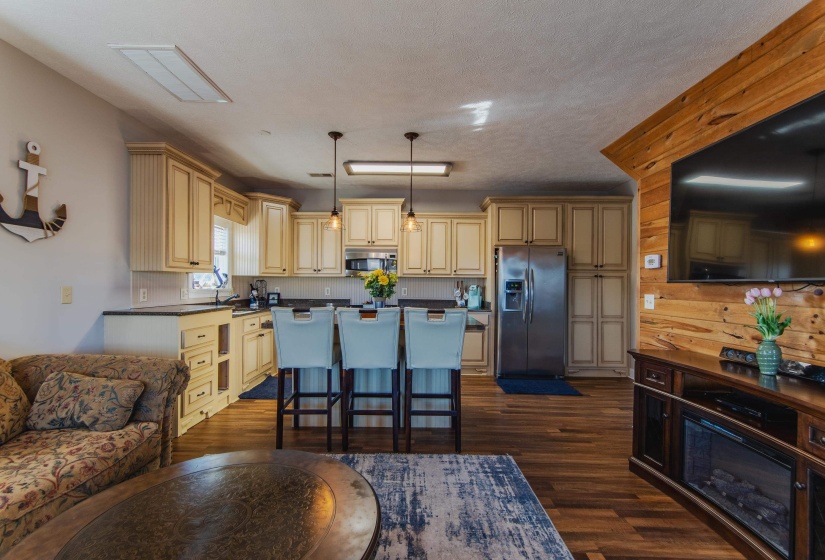 Kitchen featuring dark wood-type flooring, hanging light fixtures, stainless steel appliances, a textured ceiling, and a breakfast bar area