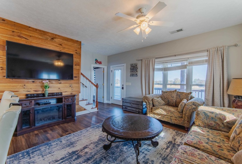 Living room featuring ceiling fan, wood walls, and dark hardwood / wood-style floors